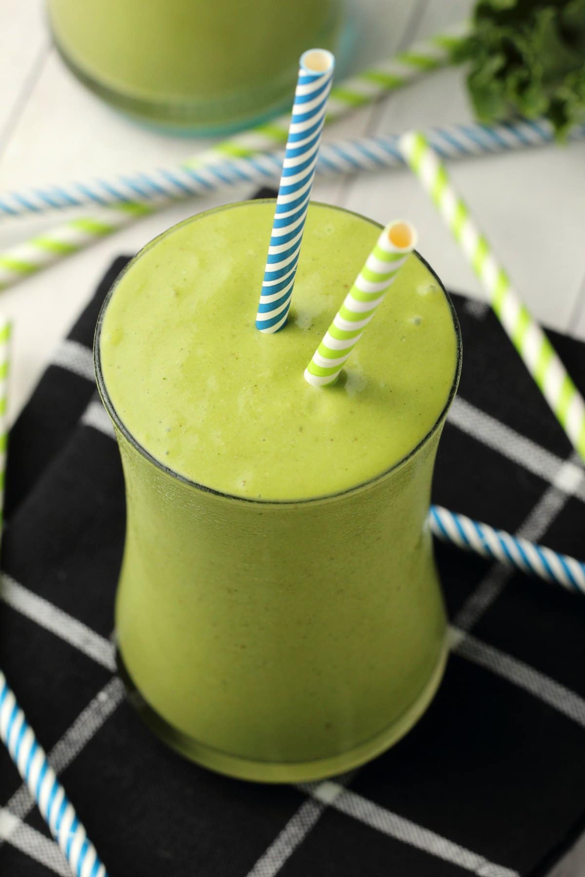 Kale Smoothie in a glass with two striped straws. 